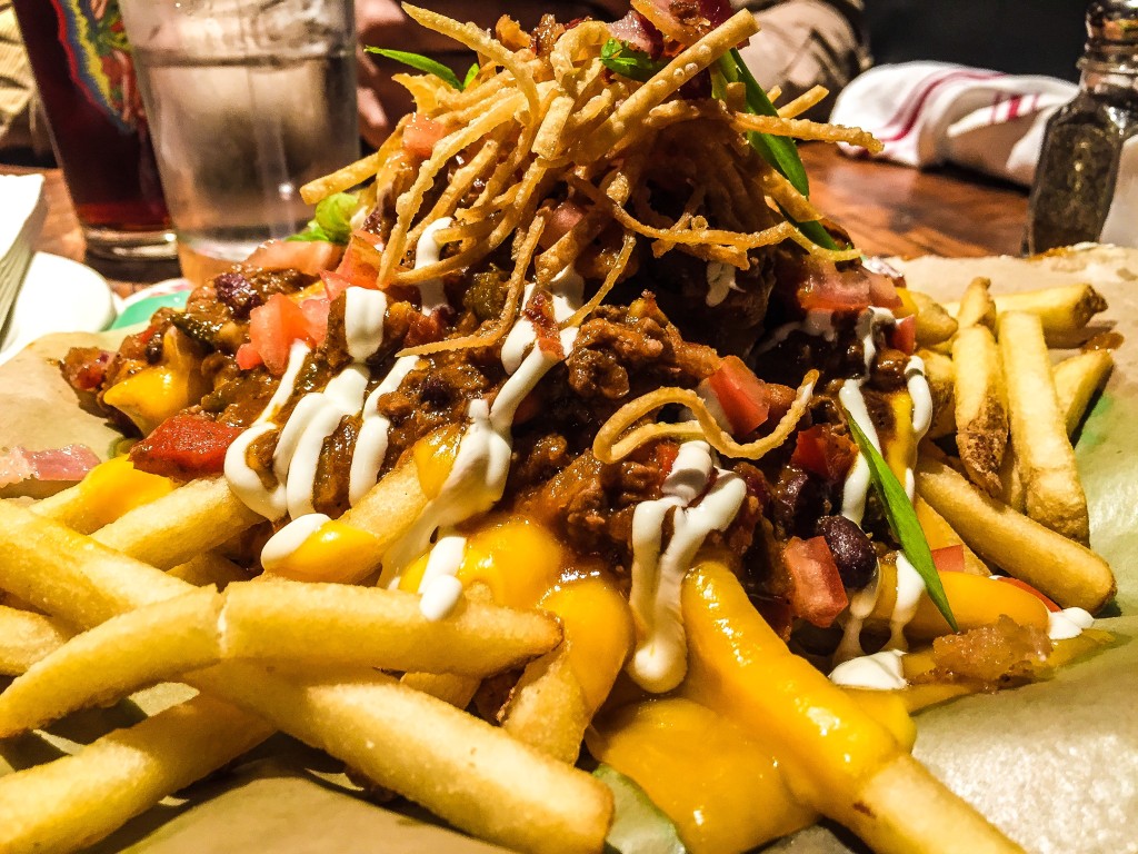 DRAGON CHILI CHEESE FRIES 12.95 Topped with Dragon’s Breath Chili, sharp cheddar cheese, diced tomatoes, scallions, sour cream + crispy bacon bits.