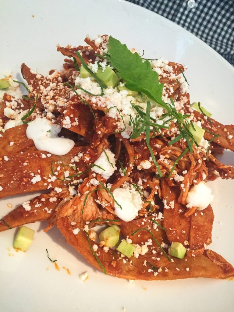 CHILAQUILES ROJOS Corn tortillas lightly fried in salsa roja, onion, cream, queso fresco, avocado with Chicken. 